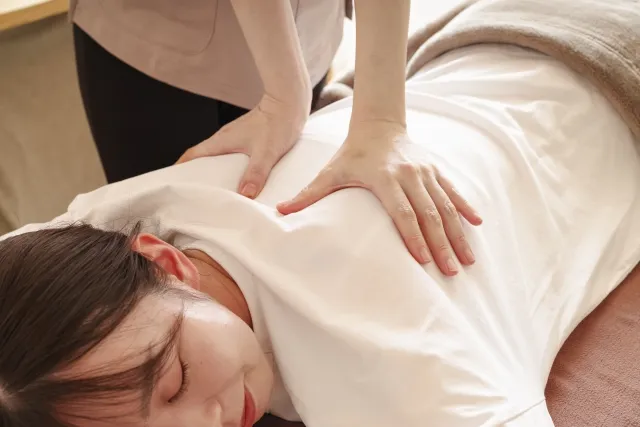 頭痛で悩む女性が整体を受ける様子