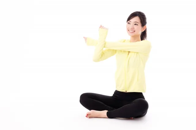 むくみ、夏のだるさを感じて、ストレッチしている女性。